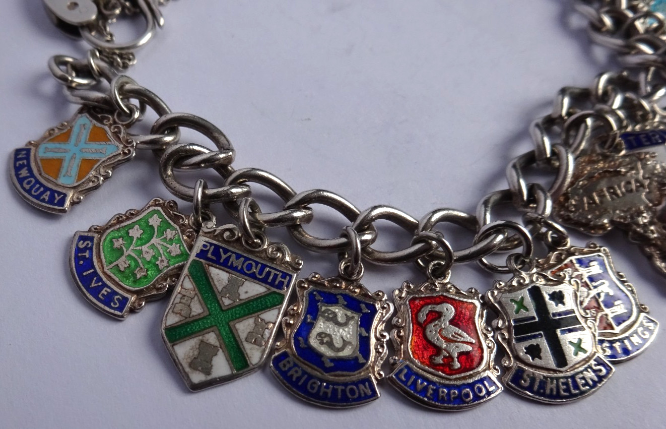 Vintage solid silver charm bracelet & numerous silver & enamel travel shields