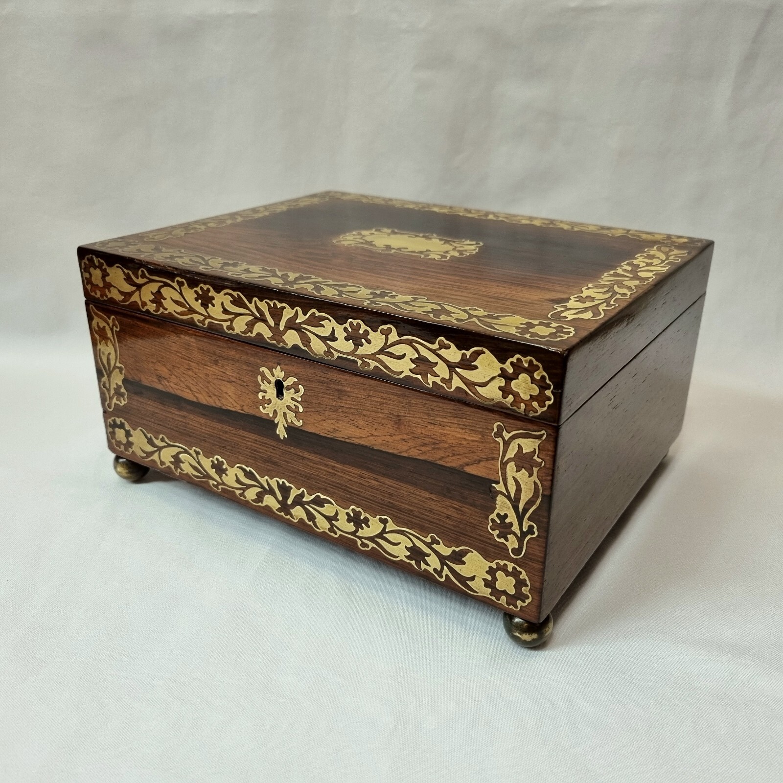 Antique rosewood jewellery or trinket box inlaid with foliate brass details.