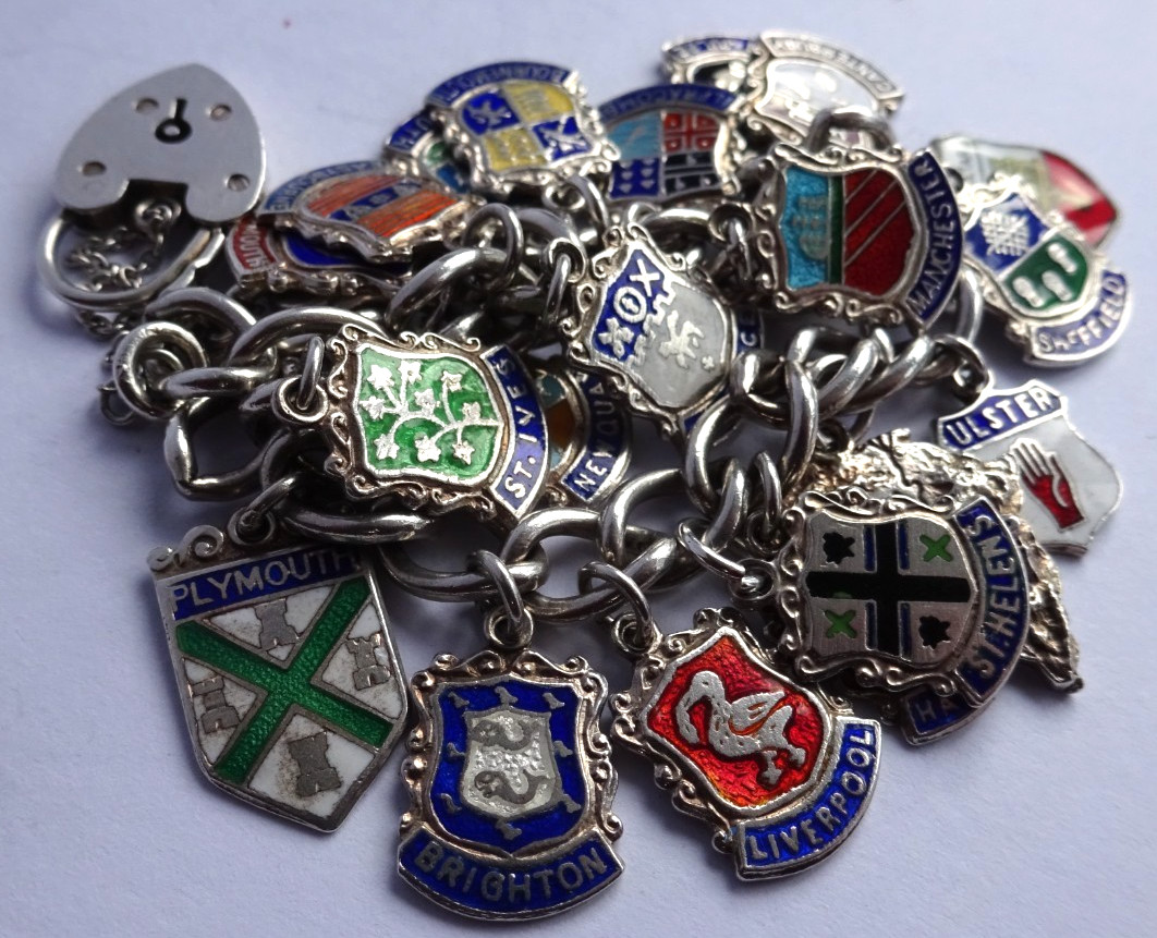 Vintage solid silver charm bracelet & numerous silver & enamel travel shields