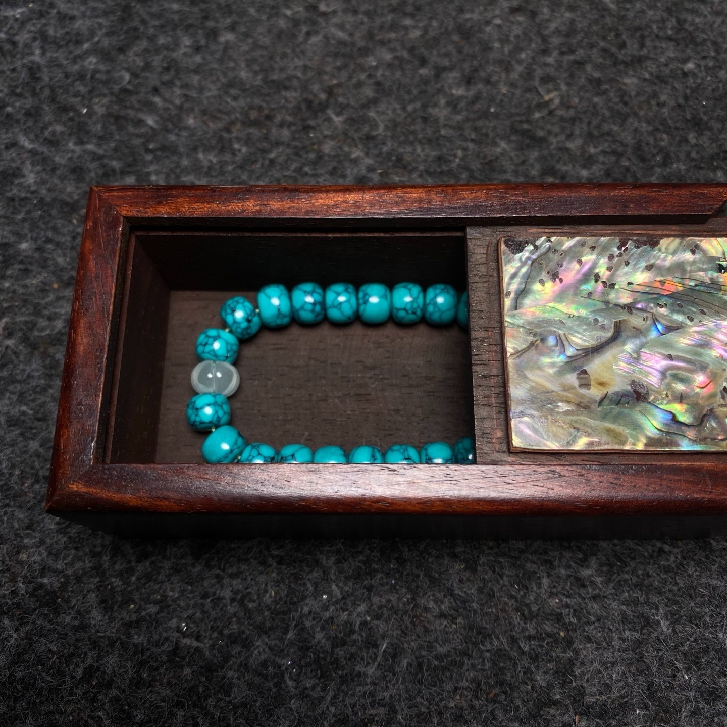 Pinestone bracelets are placed inside a rosewood inlaid with colorful shells box