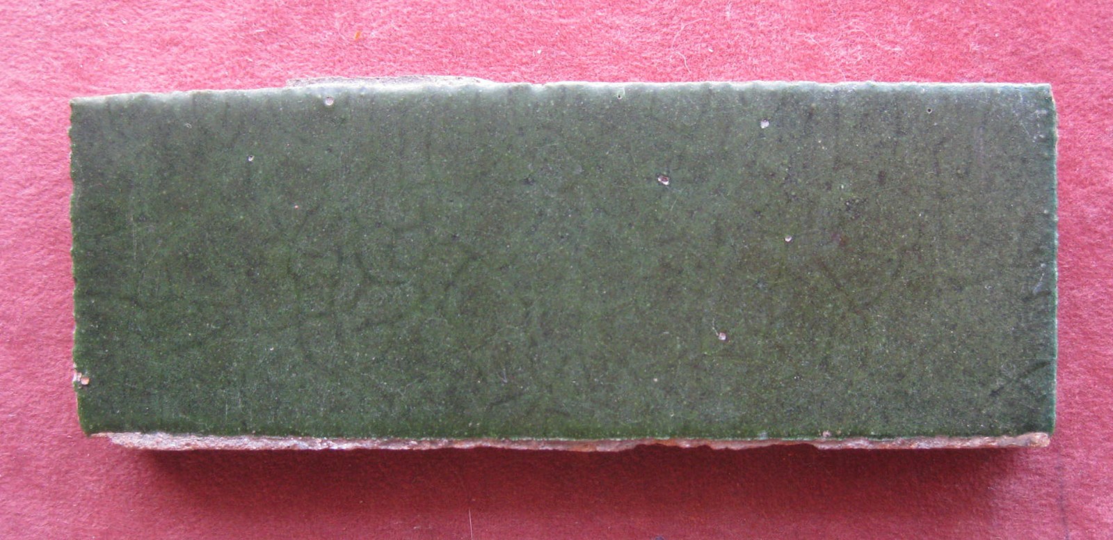 ANTIQUE GRUEBY TILE , signed, green matte glaze. 2 1/8″ x 5 5/8″