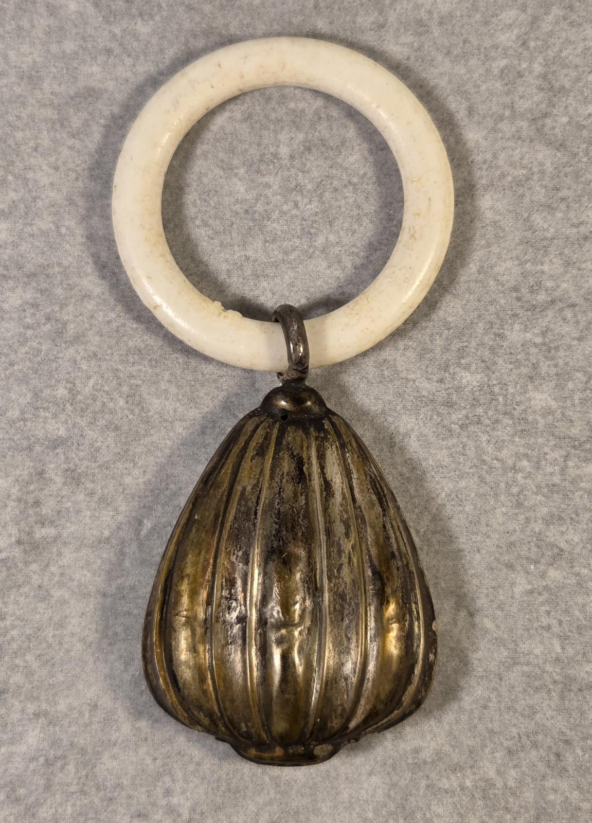 ANTIQUE BONE TEETHING RING WITH A PEAR-SHAPED .800 SILVER METAL BABY RATTLE