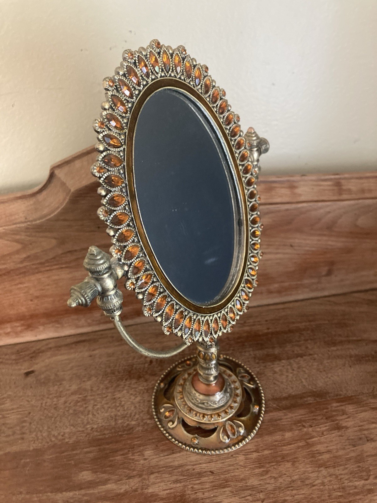vanity mirror featuring a brass-colored metal frame adorned with amber accents