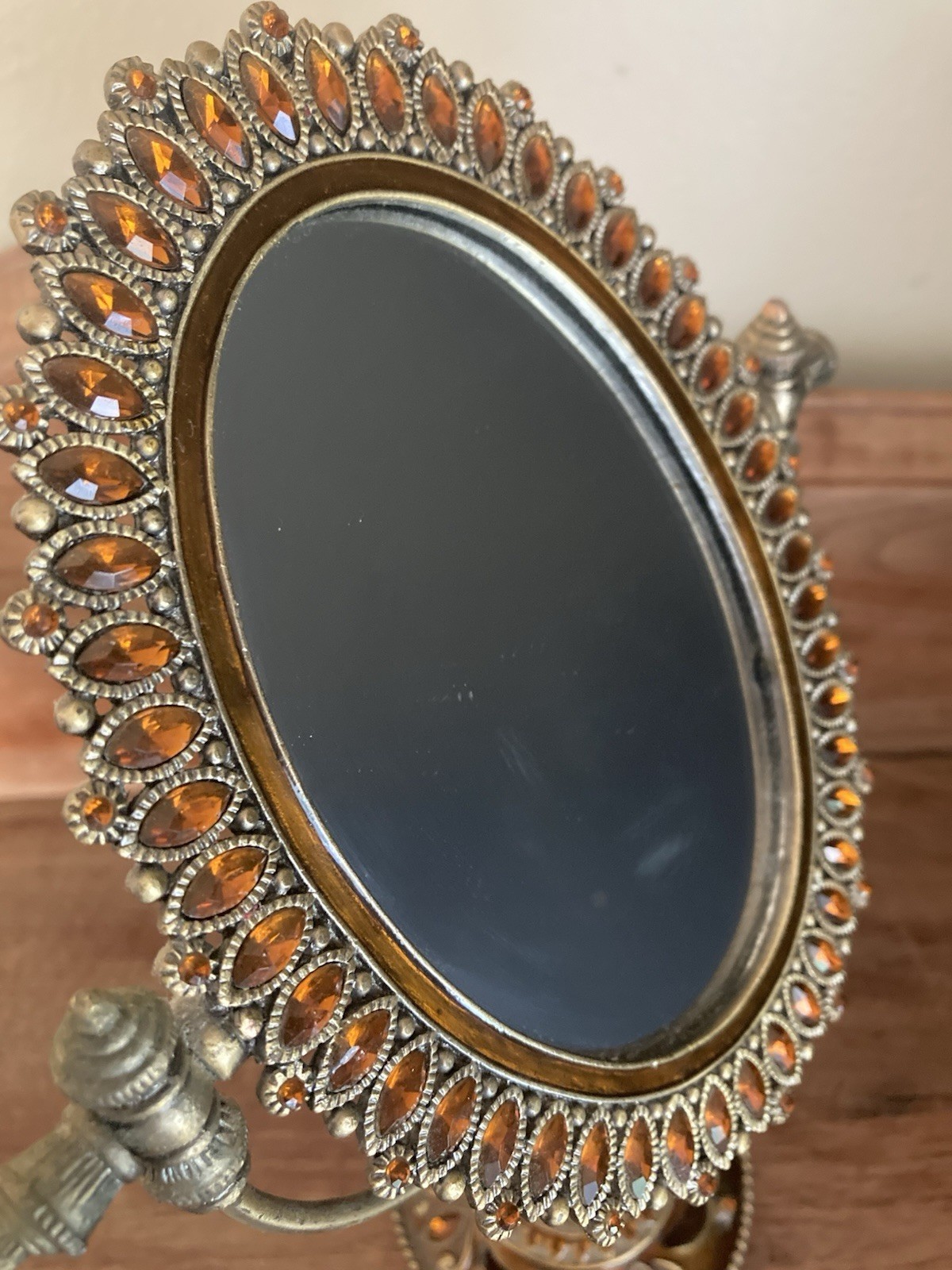 vanity mirror featuring a brass-colored metal frame adorned with amber accents
