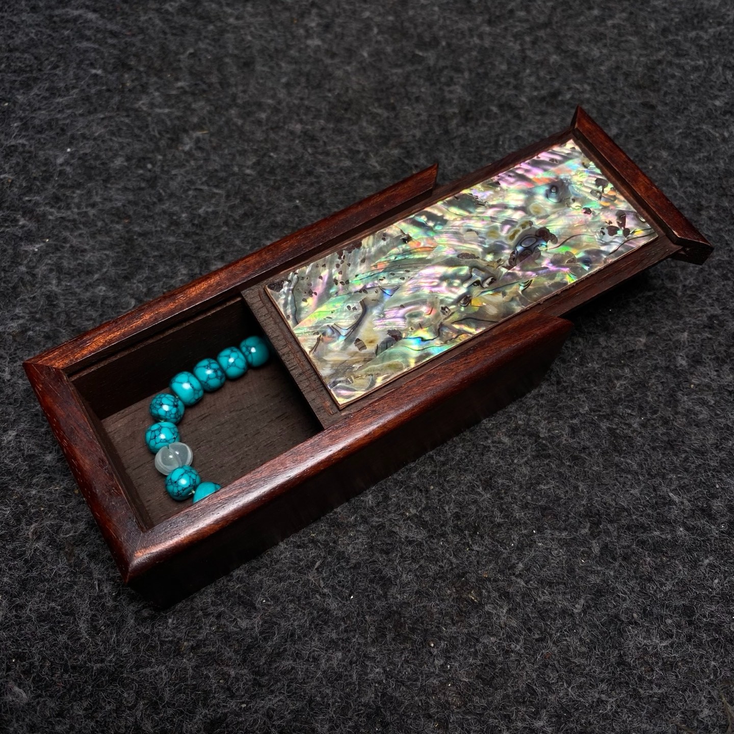 Pinestone bracelets are placed inside a rosewood inlaid with colorful shells box