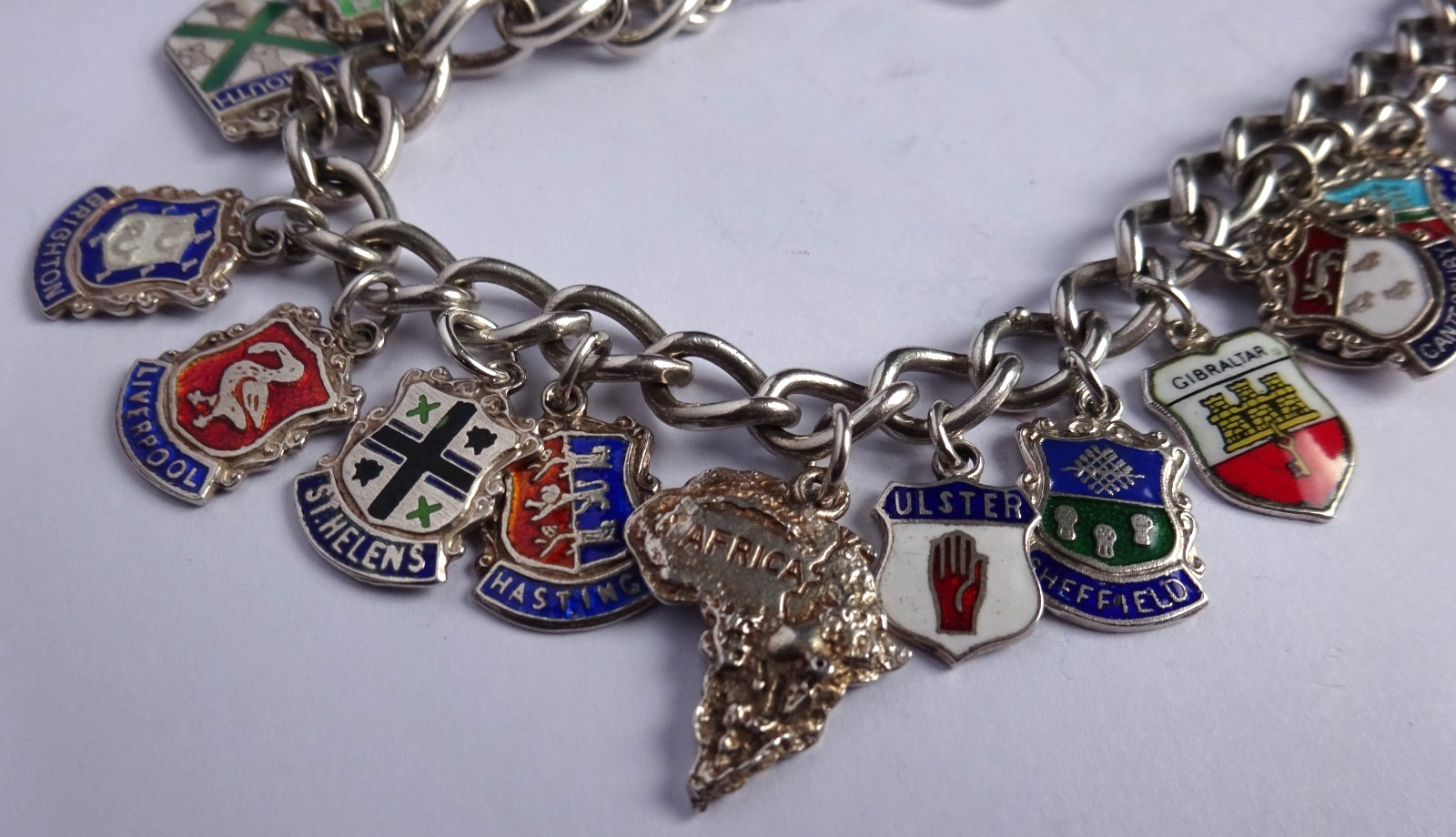 Vintage solid silver charm bracelet & numerous silver & enamel travel shields