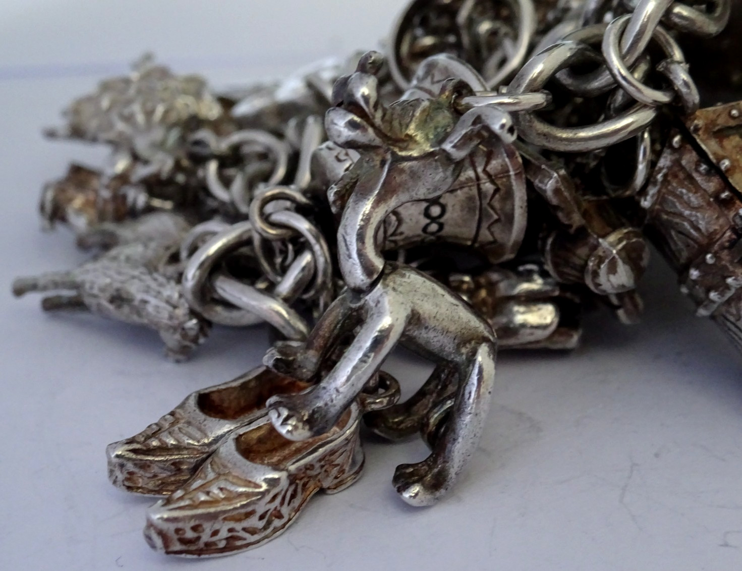 Vintage heavy solid silver charm bracelet &many curious silver charms inc moving