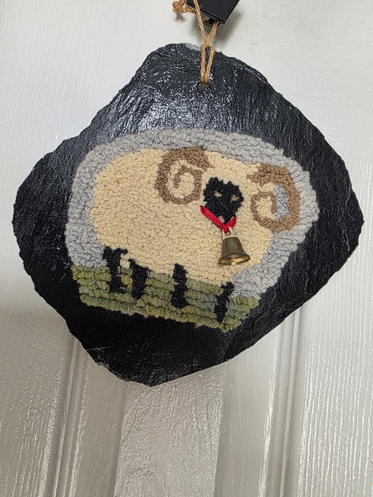 Vintage , hand-hooked rug sheep, mounted on a rustic slate or stone backing.